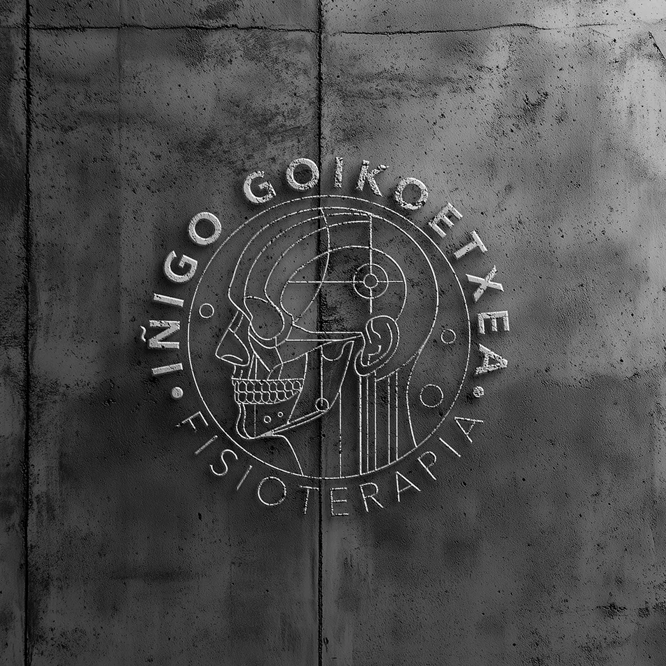 Iñigo Goikoetxea Fisioterapia logo embossed on a concrete wall, showing a line-art anatomical skull inside circular lettering, identity design